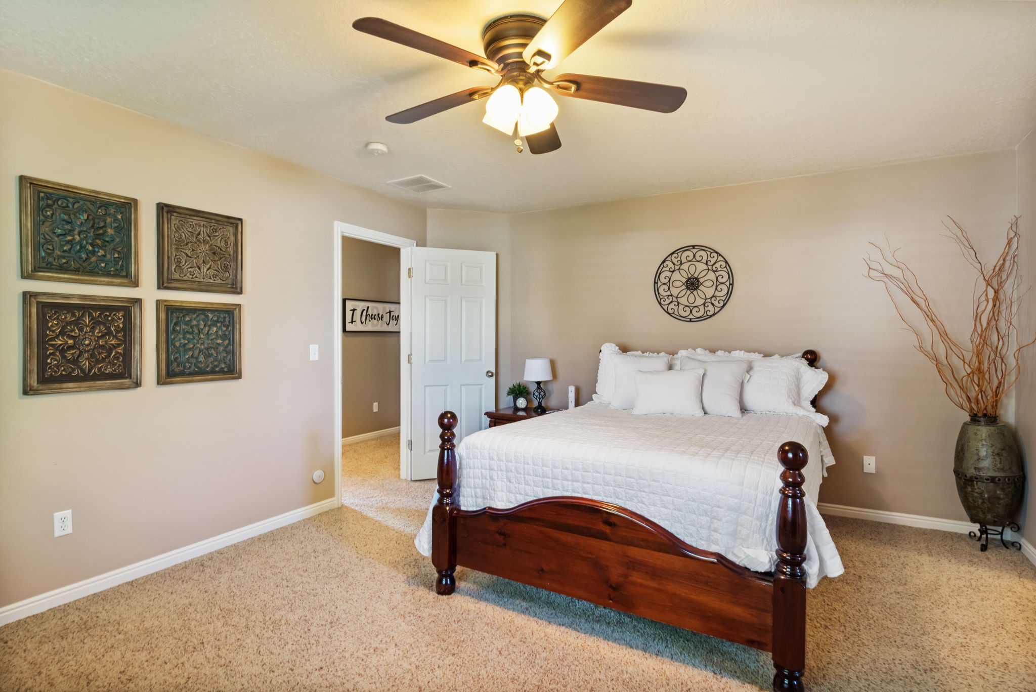 Master bedroom featuring a ceiling fan with integrated lighting, neutral wall tones, white trim, and a white interior door