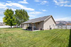 Expansive backyard featuring a covered patio, manicured lawn, mature trees, and privacy fencing