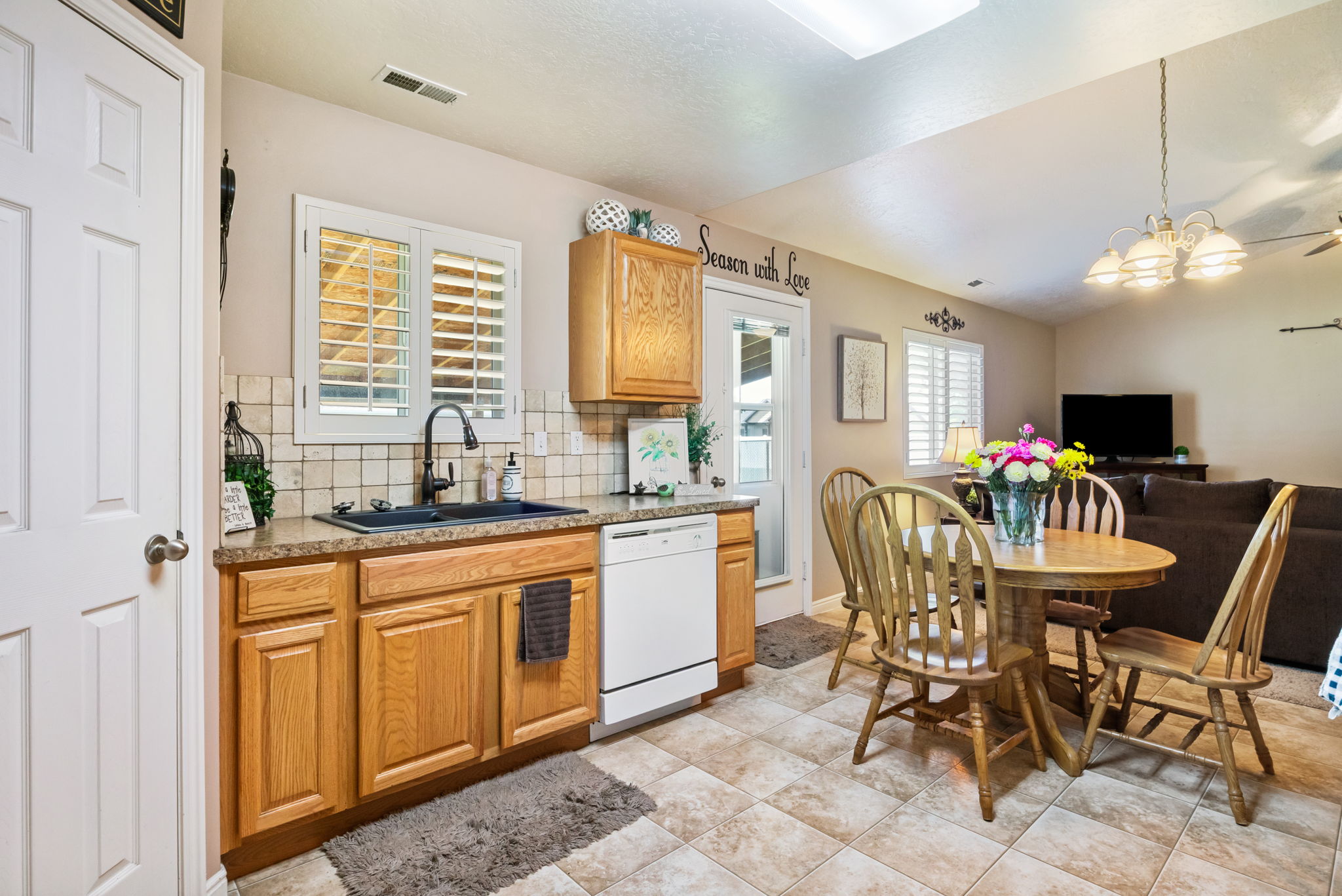 Kitchen featuring wood-finish cabinetry, granite-style countertops, a black sink with a black faucet, and a white dishwasher