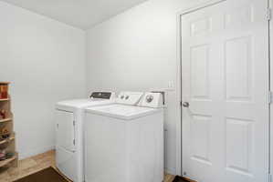 Dedicated laundry space with neutral tile flooring, white walls, and a paneled door