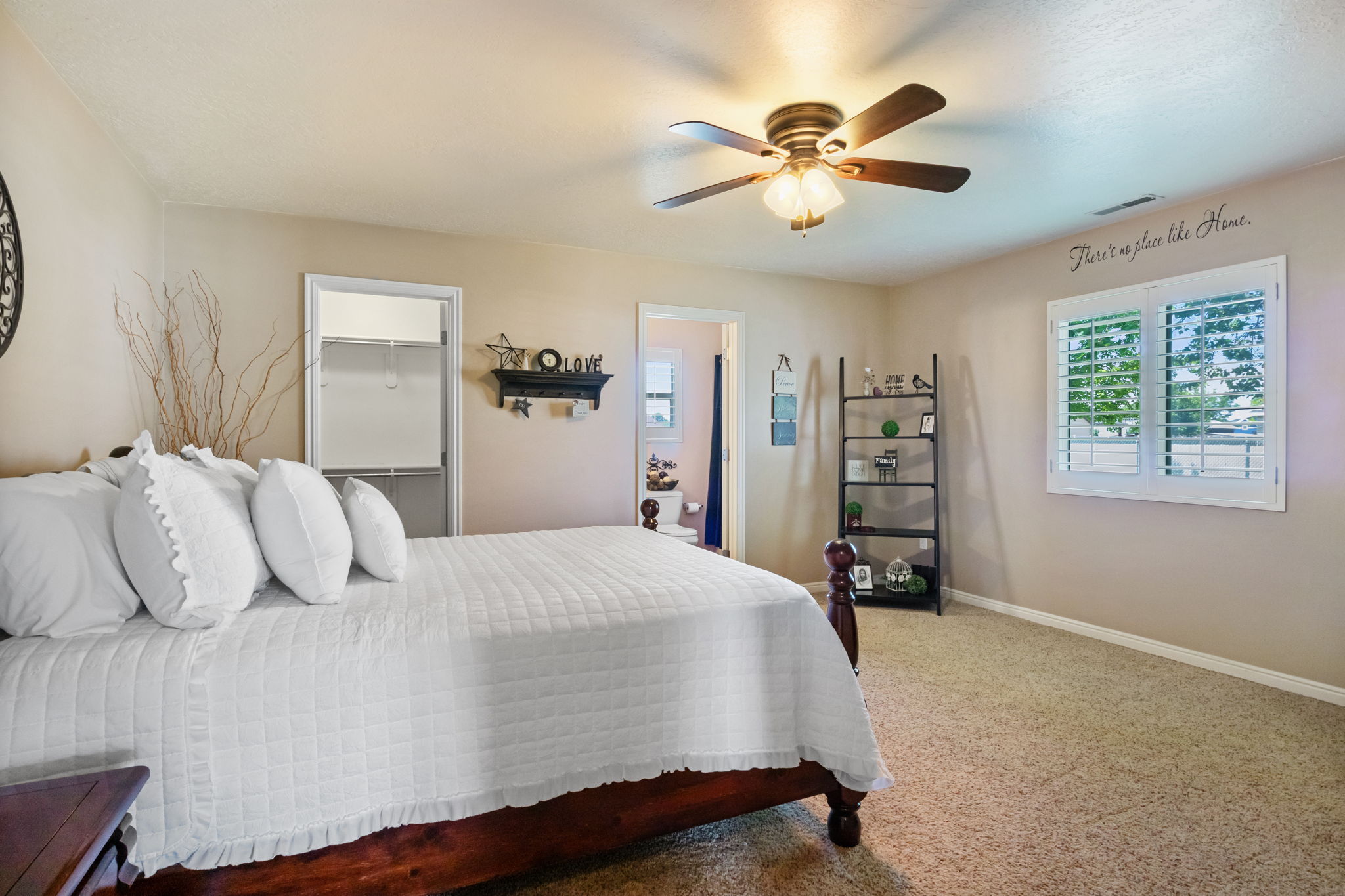 Master bedroom featuring a ceiling fan with light fixture, window with white plantation shutters, and a closet with built-in shelving