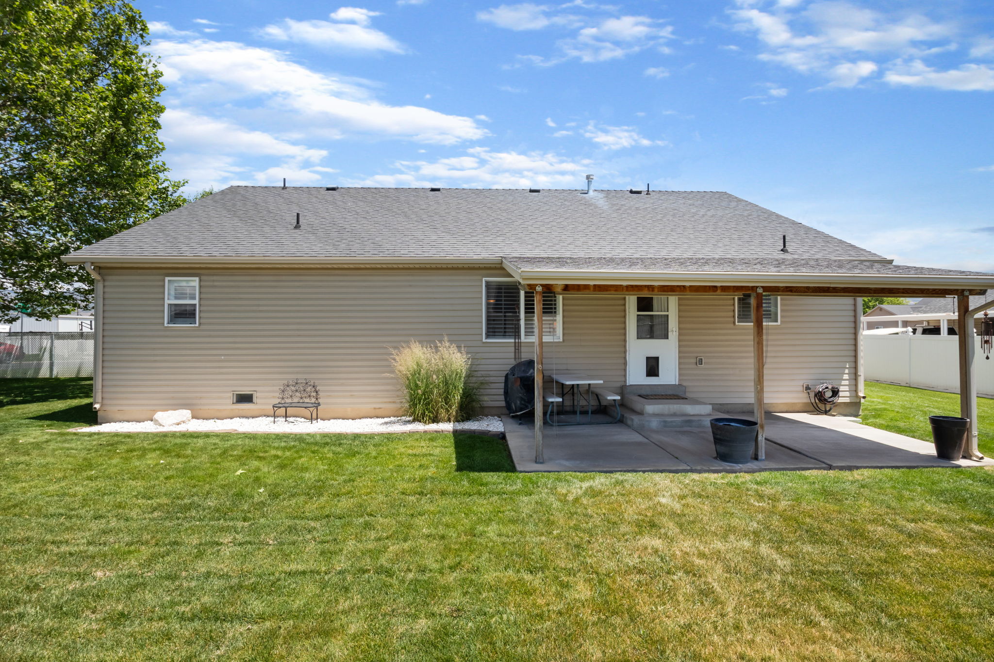 Spacious backyard featuring a covered patio, extensive lawn, and gravel landscaping