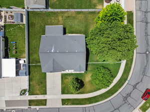 Aerial view of a residential property featuring a gray shingled roof, a paved driveway, and established trees