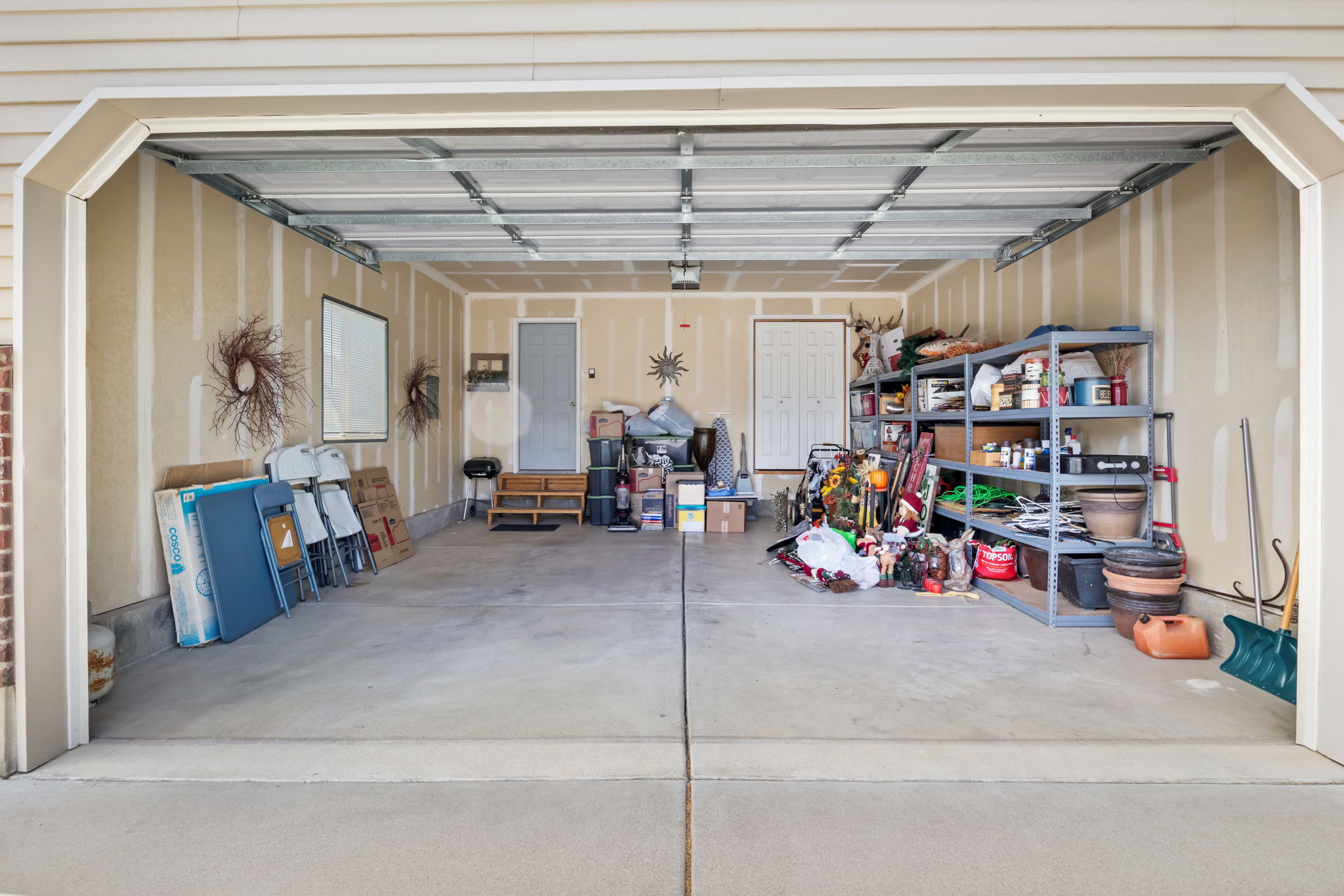 Two-car garage featuring a concrete floor, unpainted drywall, and a ceiling with exposed framing