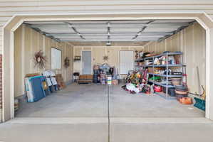 Two-car garage featuring a concrete floor, unpainted drywall, and a ceiling with exposed framing