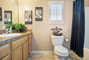 Full Master Bathroom featuring a single vanity with an integrated sink, wood-finish cabinetry, and a speckled countertop