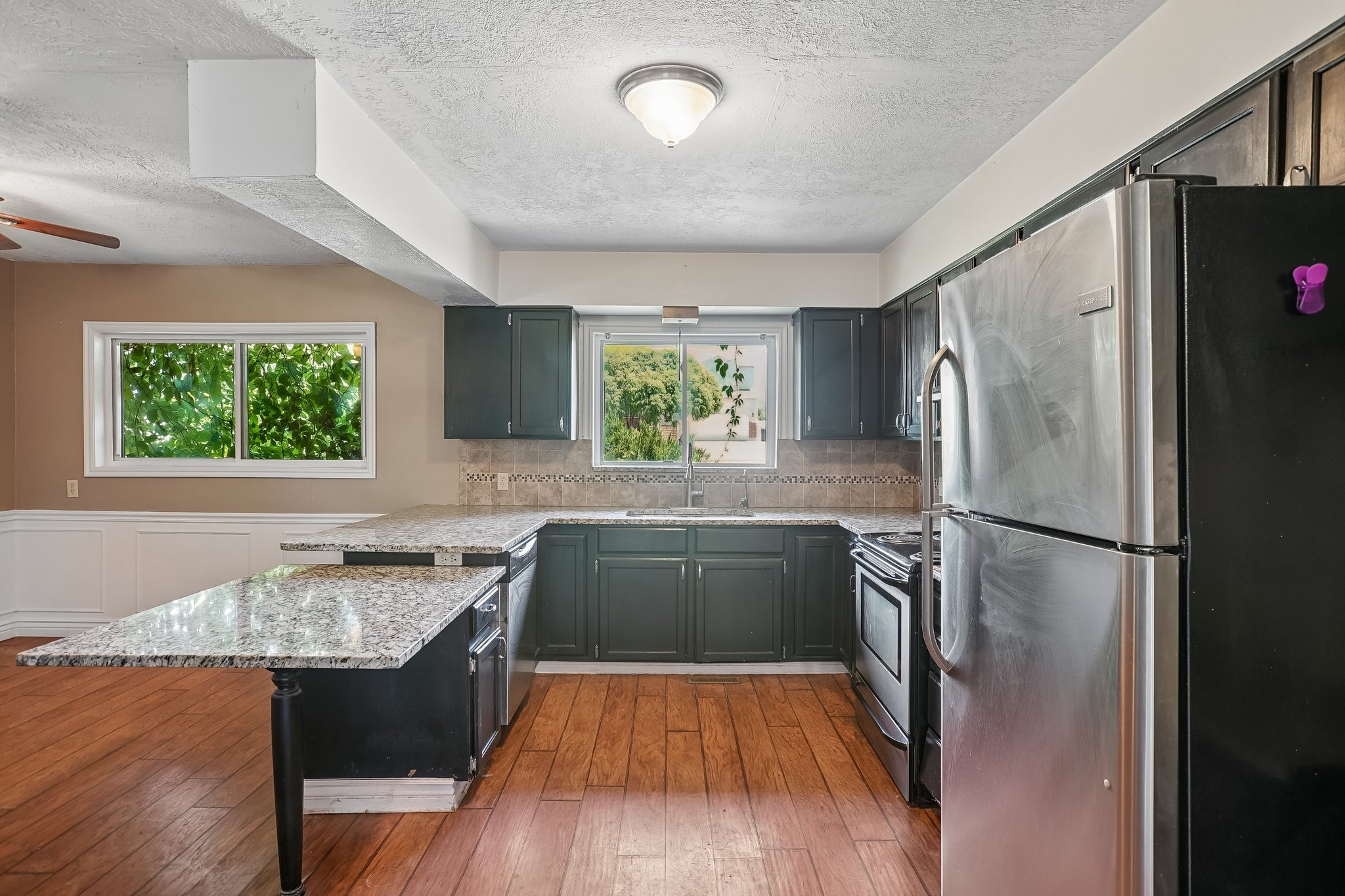 Kitchen featuring wood-finish flooring, dark cabinetry, and light-colored countertops