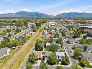 Residential neighborhood with single-story and two-story homes, mature trees, and a clear sky