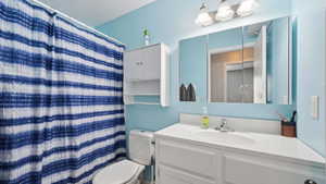 Bathroom featuring a white vanity with an integrated sink, tri-panel mirrored medicine cabinet, and a wall-mounted storage cabinet with open shelving