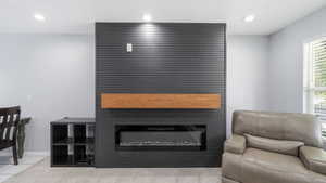 Feature wall with horizontal slat paneling, integrated electric fireplace, wood-finish floating mantel, and recessed ceiling lighting