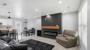 Living area featuring an electric fireplace with a wood mantle, shiplap accent wall, and recessed lighting