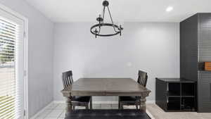 Bright room featuring a glass-paned door with blinds, white square floor tiles, and a contemporary chandelier