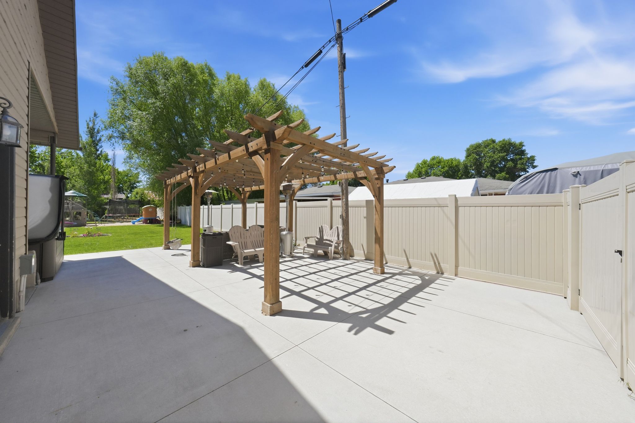 Expansive concrete patio featuring a large wooden pergola