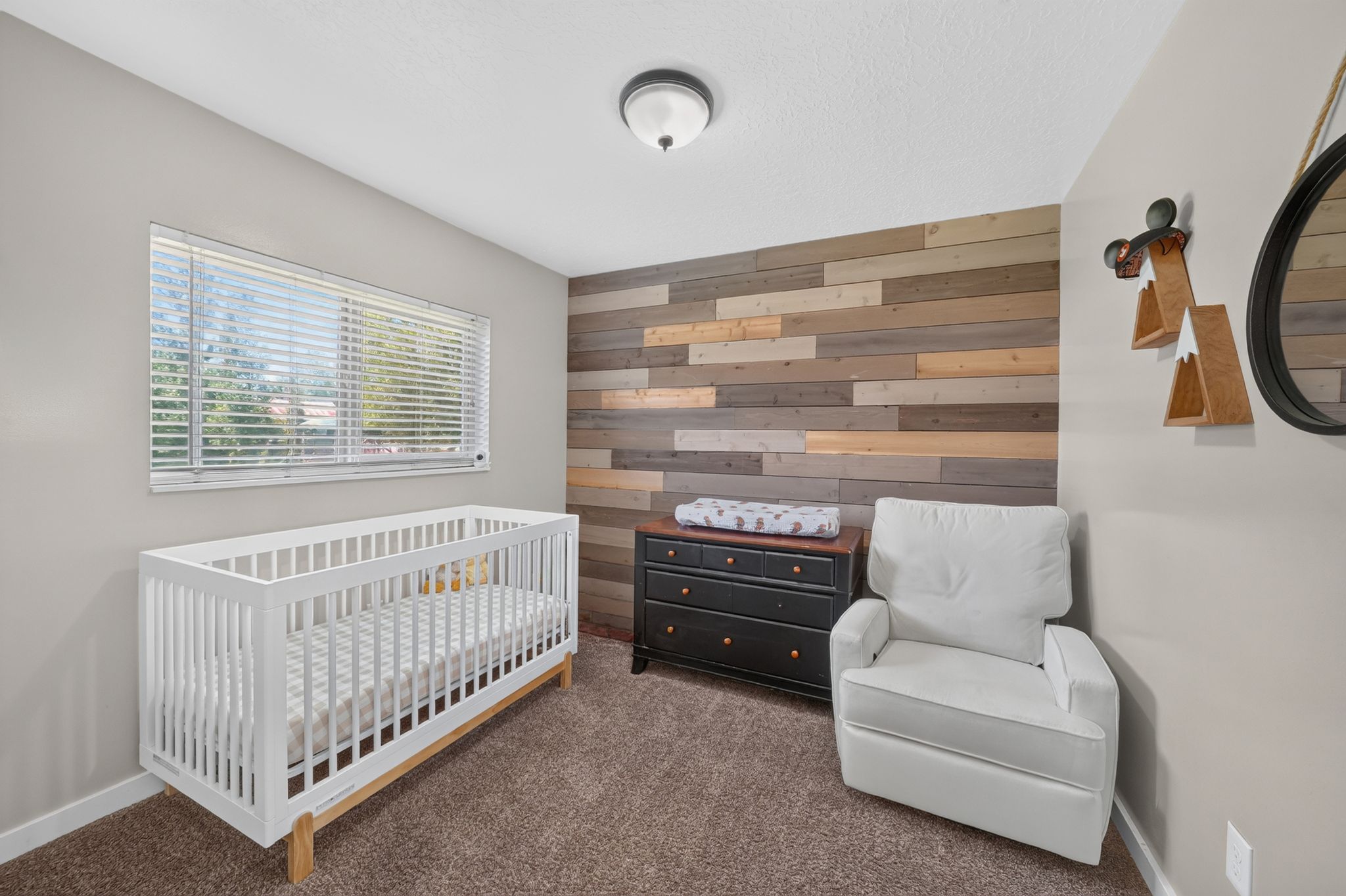 Bedroom featuring a horizontal plank accent wall, neutral wall paint, textured carpeting, and a window with blinds