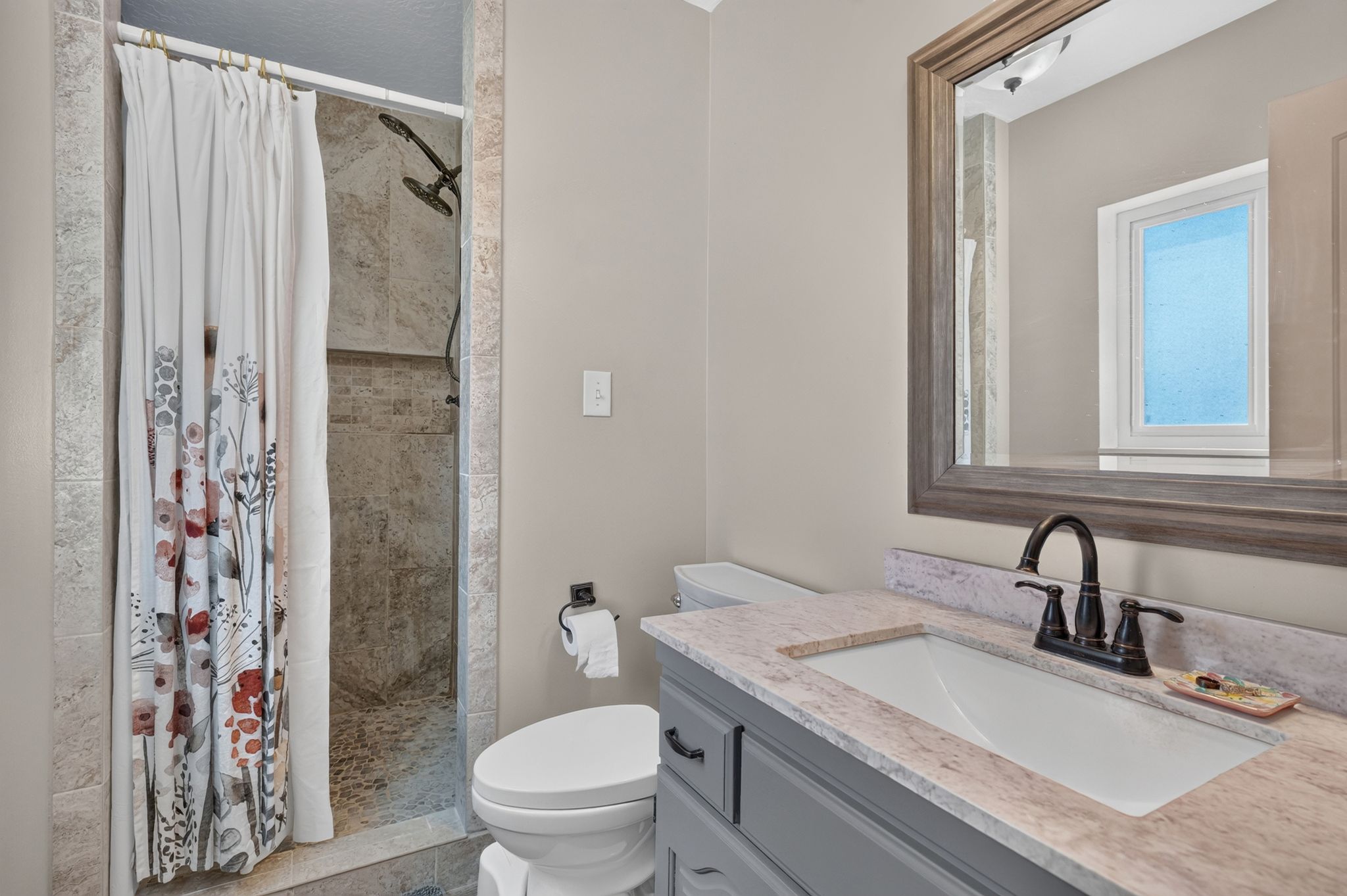 Primary Bathroom featuring Vanity with light-toned countertop and integrated sink, complemented by a bronze-finish faucet
