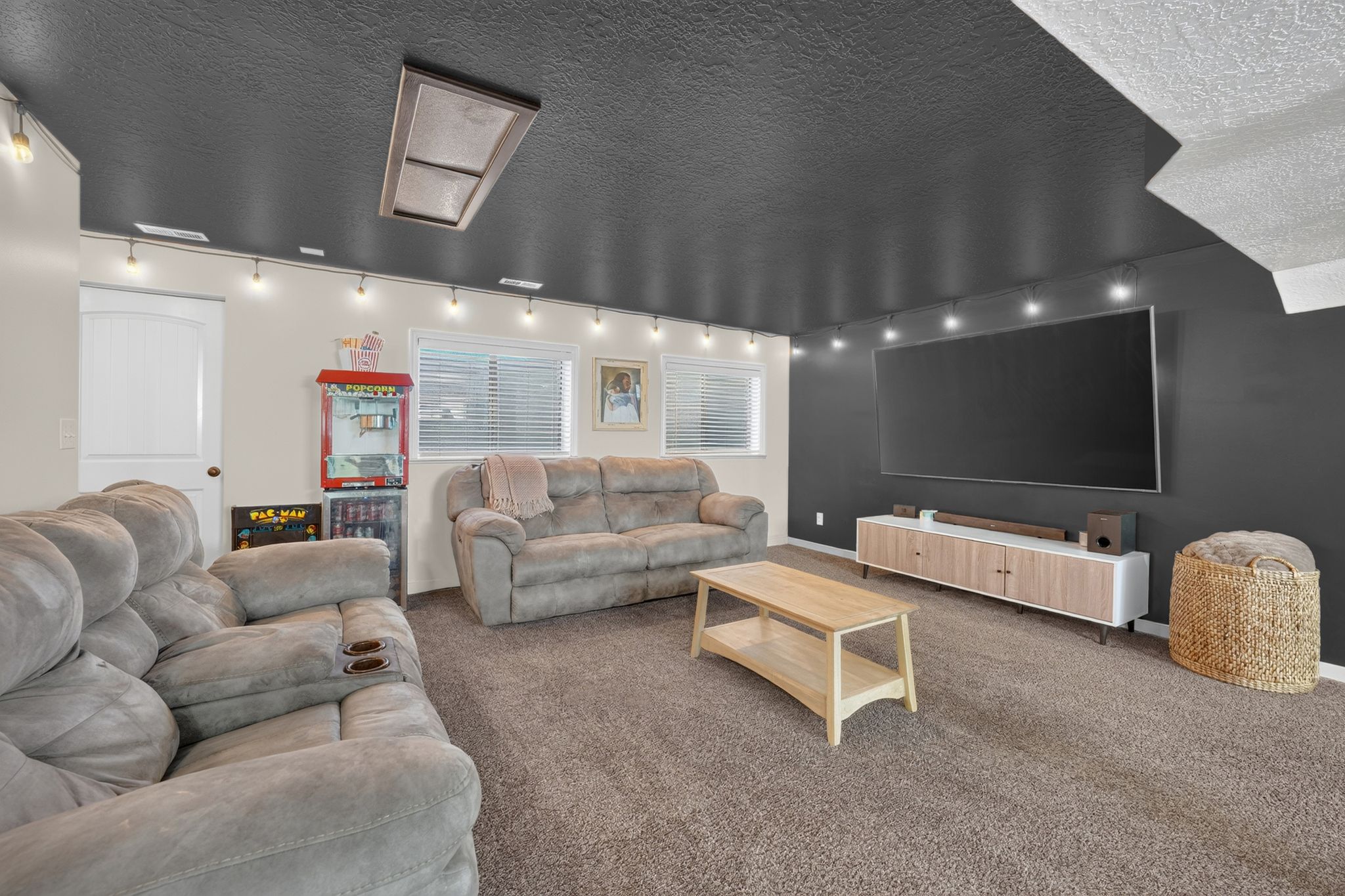 Spacious room featuring dark carpeting and a dark ceiling with track lighting