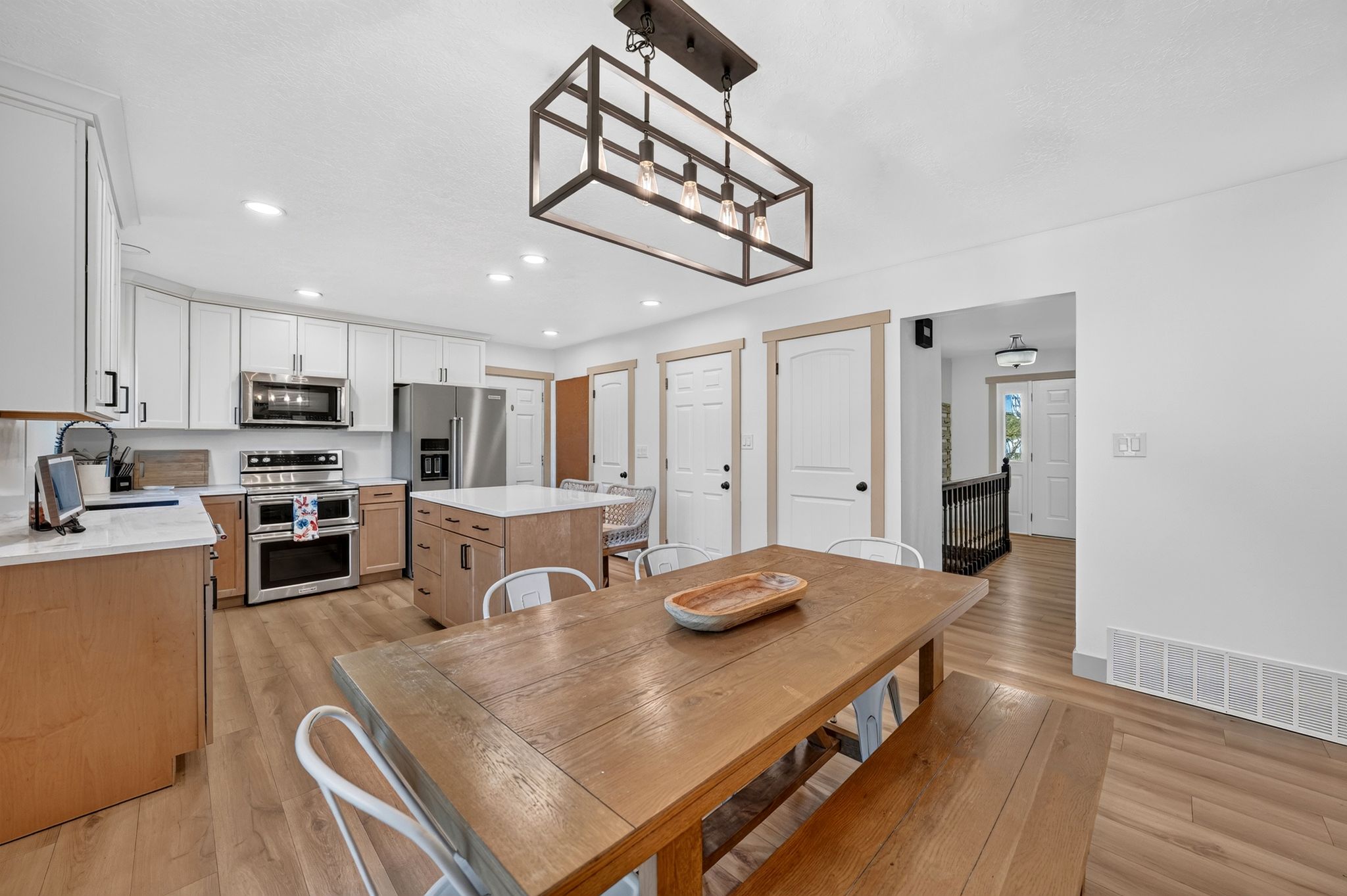 Kitchen featuring an island, stainless steel appliances, wood-finish flooring, and white cabinetry