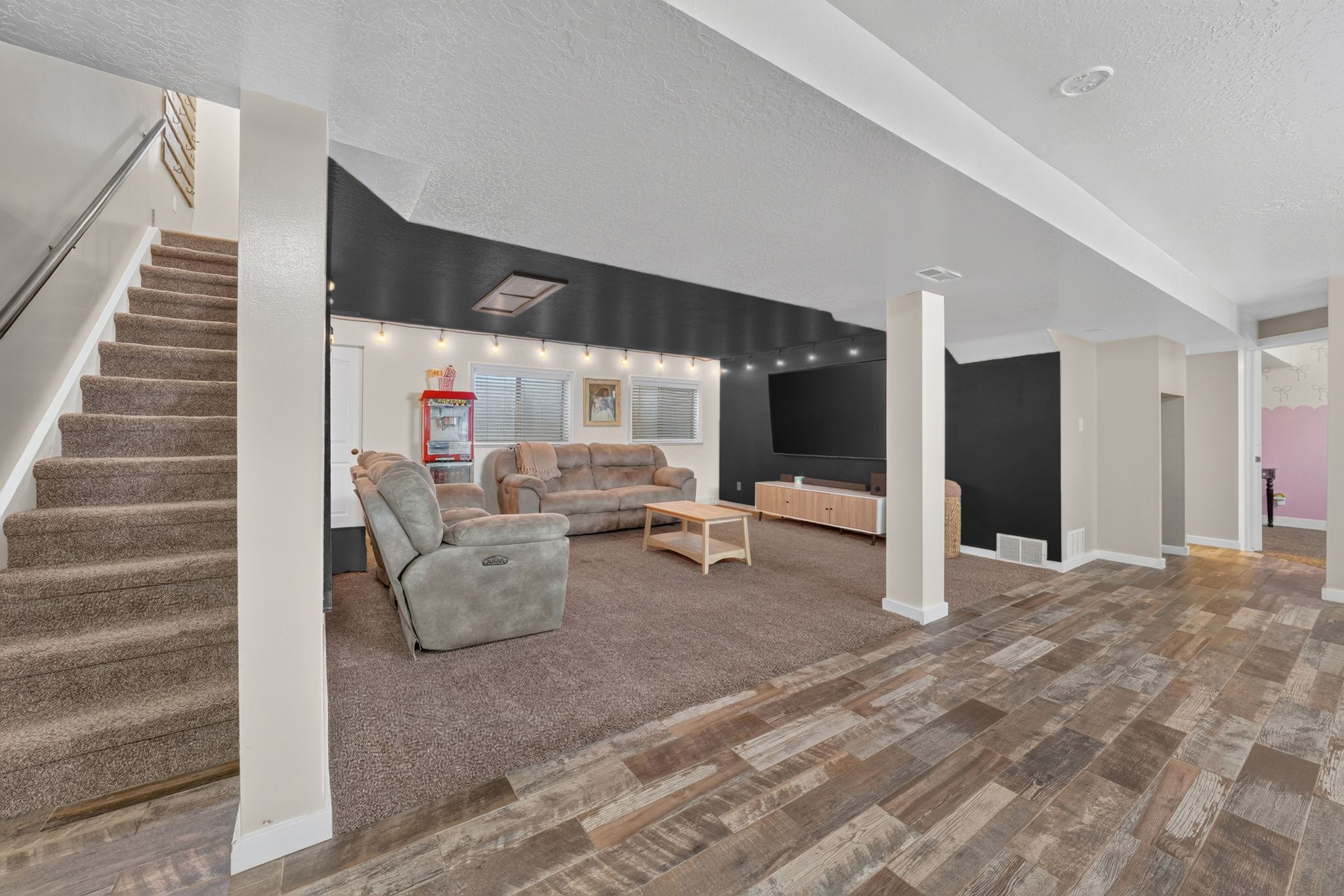 Spacious recreational room featuring wood-finish flooring, recessed lighting, and a dark accent wall