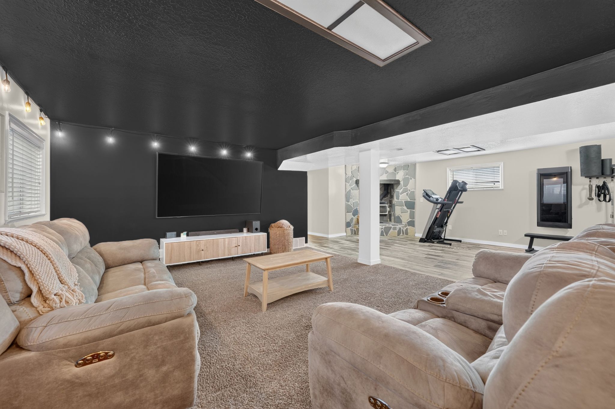 Expansive recreation room featuring a neutral carpeted area and contrasting light wood-finish flooring
