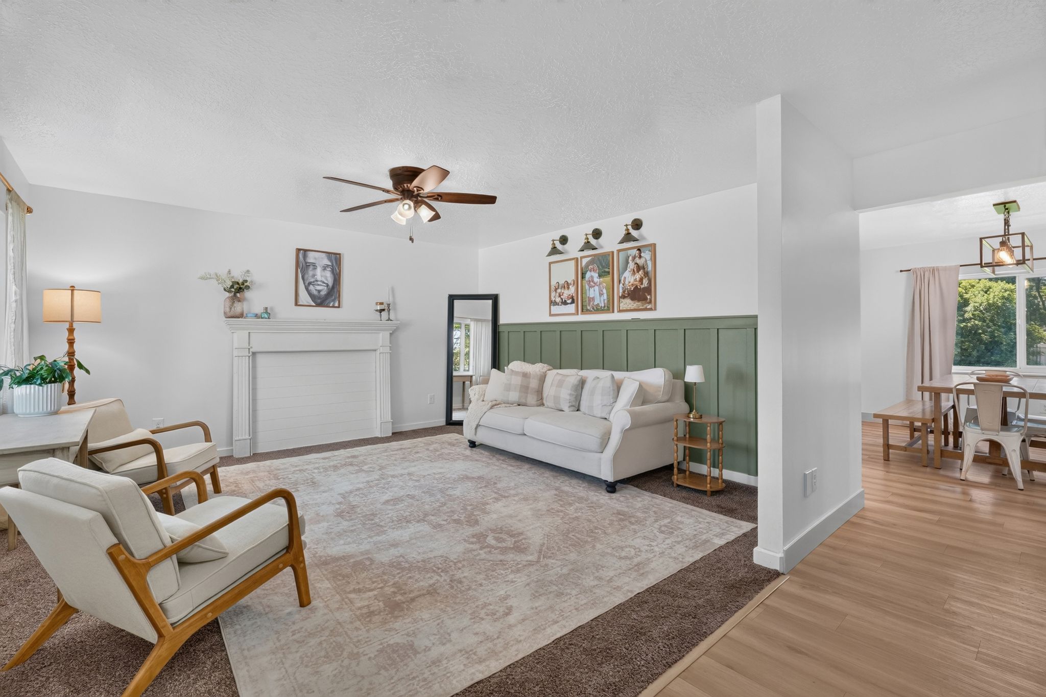 Living area featuring a white fireplace with mantel, ceiling fan with integrated lighting, and board and batten accent wall