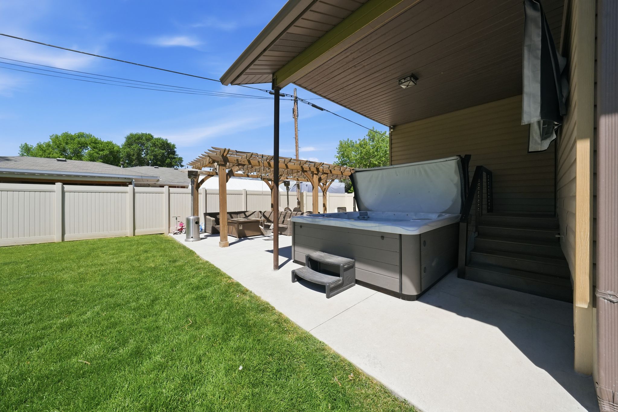 Manicured lawn with a concrete patio, wooden pergola, and privacy fencing