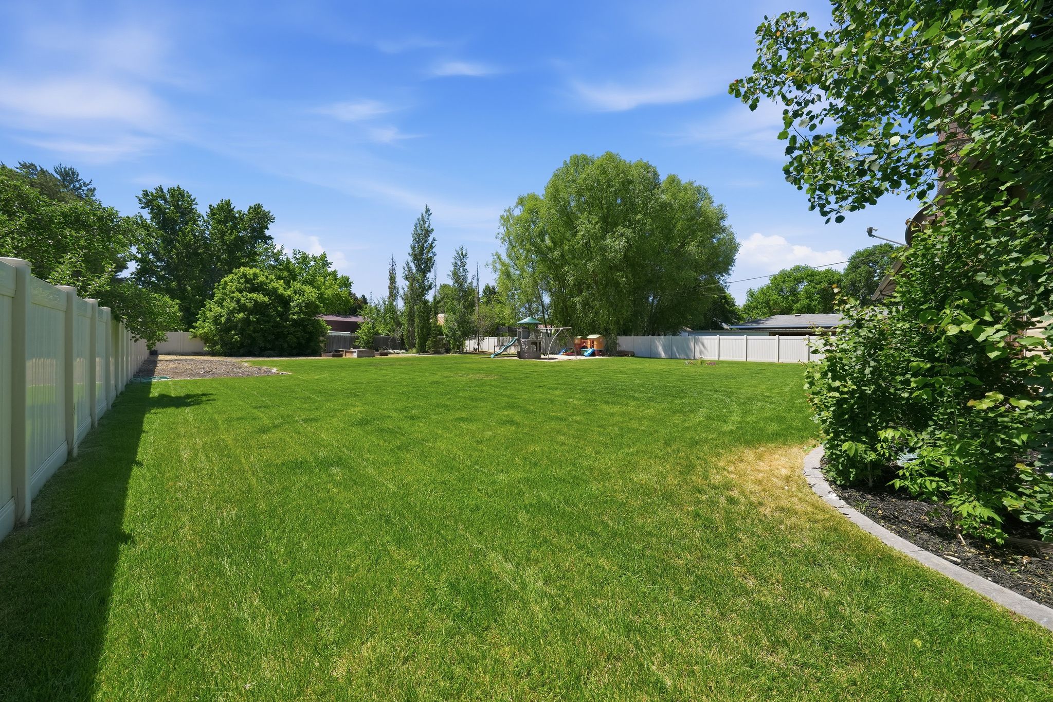 Expansive green lawn with mature perimeter trees and shrubs