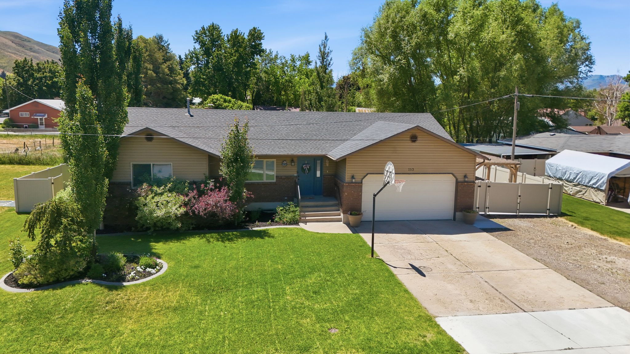 Ranch-style residence featuring a prominent two-car garage with an automatic door, beige siding, and a dark shingle roof