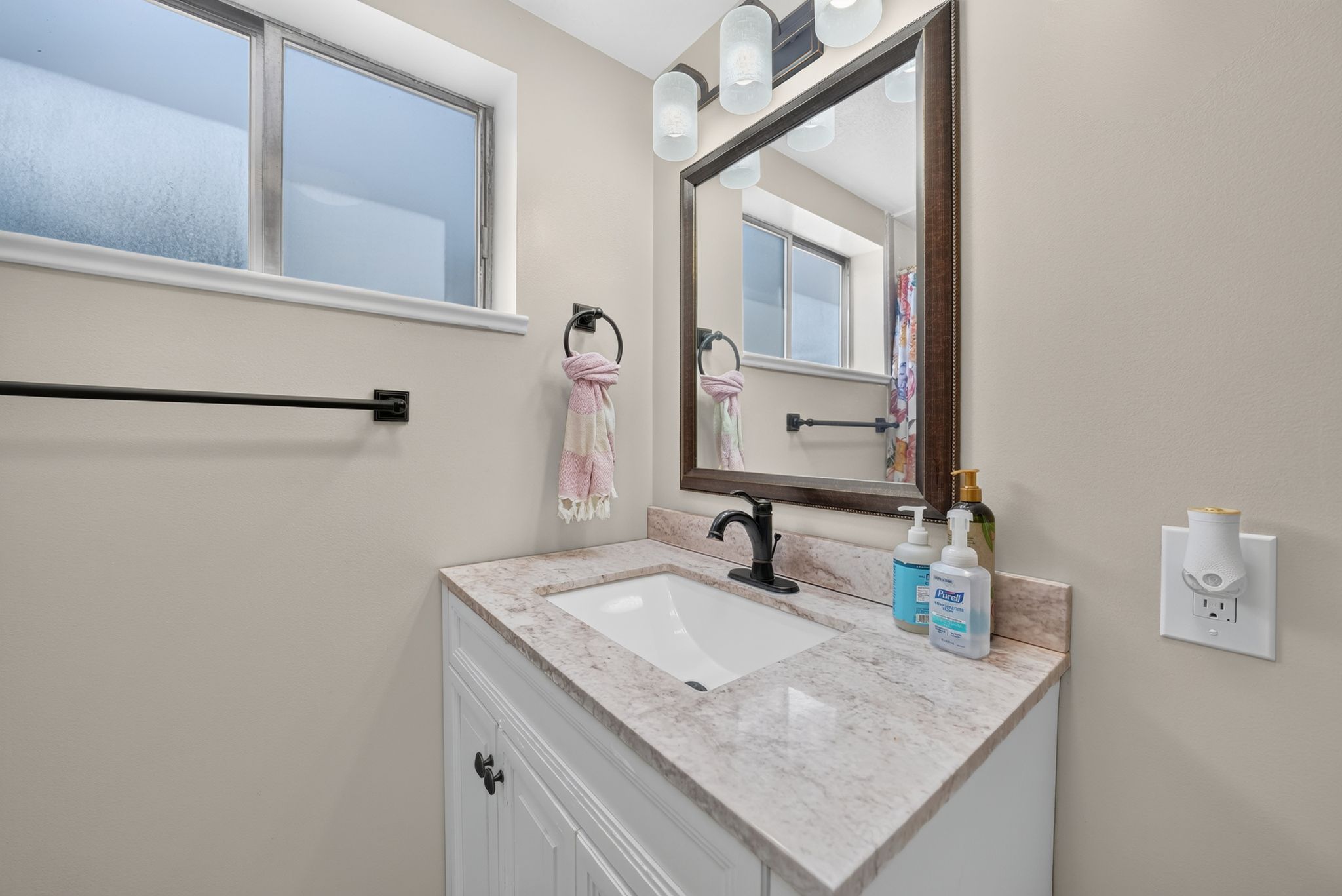 Bathroom featuring a white vanity with paneling, a light-colored stone-finish countertop, and an undermount sink