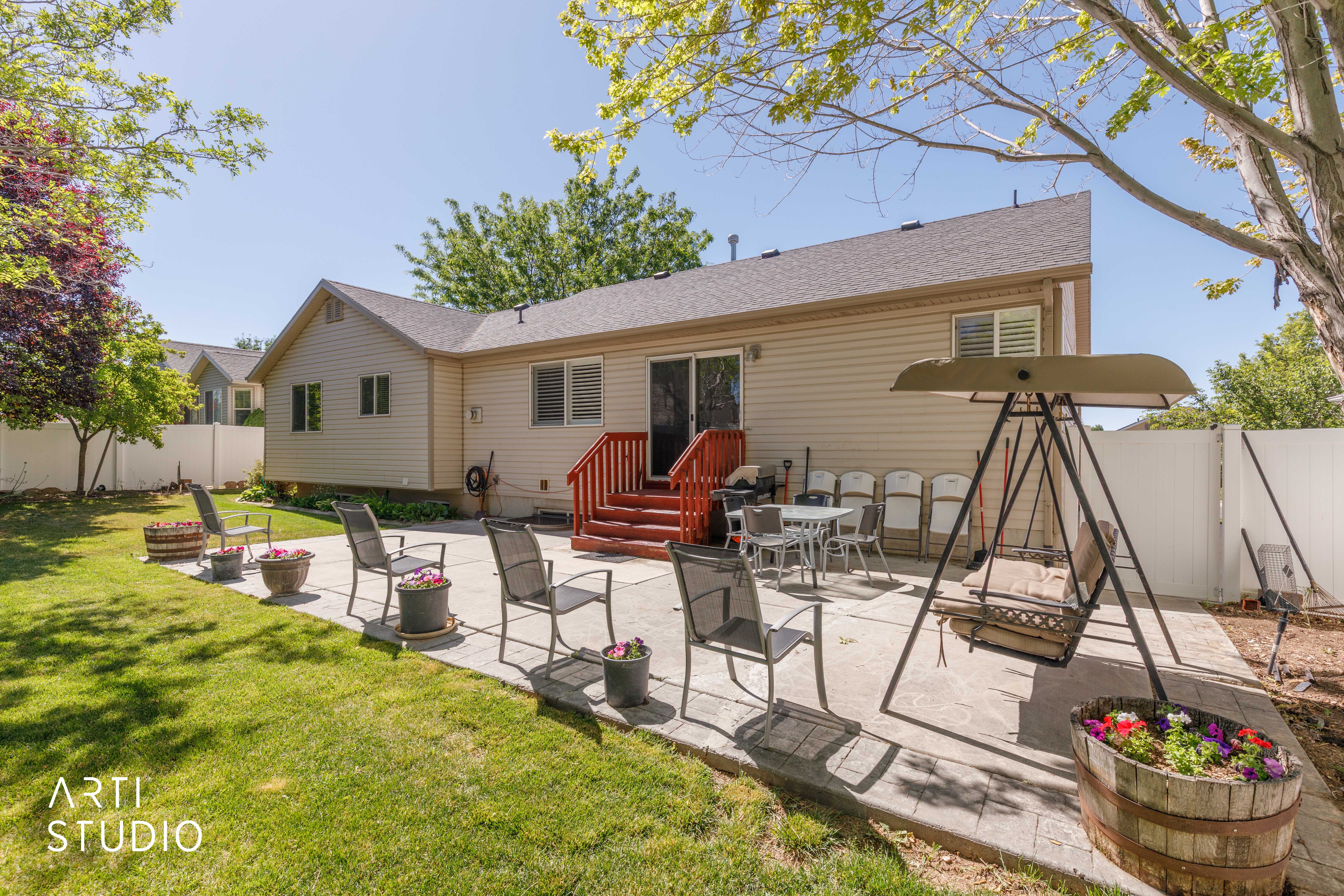 Expansive backyard featuring a stamped concrete patio, a manicured lawn, a privacy fence, and mature trees
