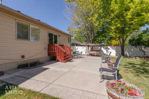 Expansive concrete patio area with a red-stained wood deck and stairway