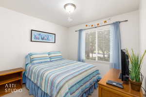 Carpeted room with a single window featuring horizontal blinds and sheer blue curtains