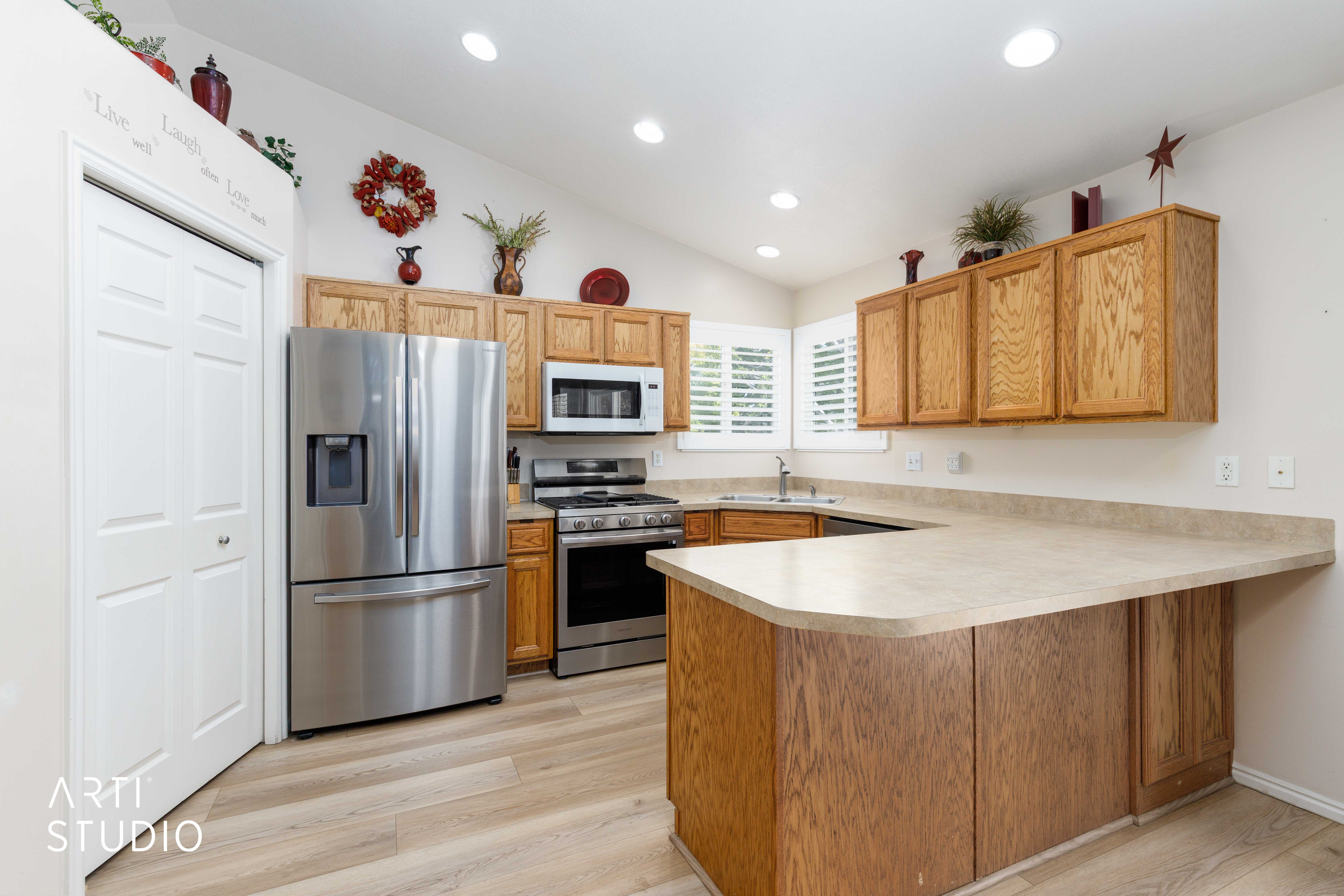 Kitchen featuring light wood-finish flooring, vaulted ceiling, recessed lighting, wood cabinetry, stainless steel appliances, and L-shaped counter space