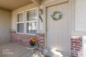 Inviting front entry featuring a paneled door, brick wainscoting, and an overhead porch light