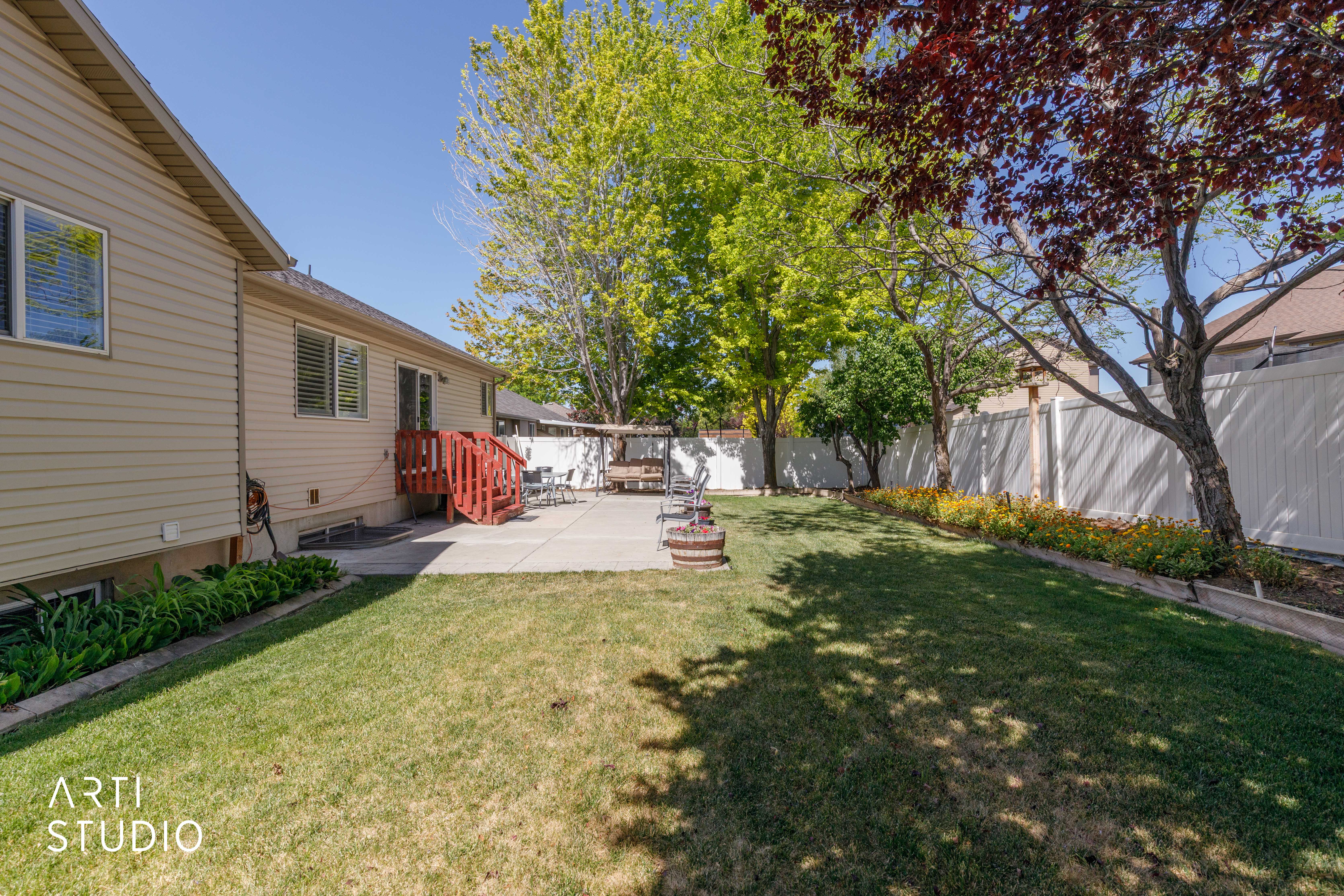 Expansive backyard featuring a manicured lawn, concrete patio, and mature trees