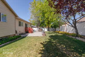 Expansive backyard featuring a manicured lawn, concrete patio, and mature trees