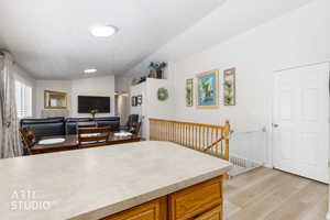 Open concept living area featuring wood-finish flooring, a kitchen island with stone-look countertop, and a wooden banister