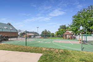 Multi-sport court featuring a basketball hoop and painted lines, surrounded by a chain-link fence.