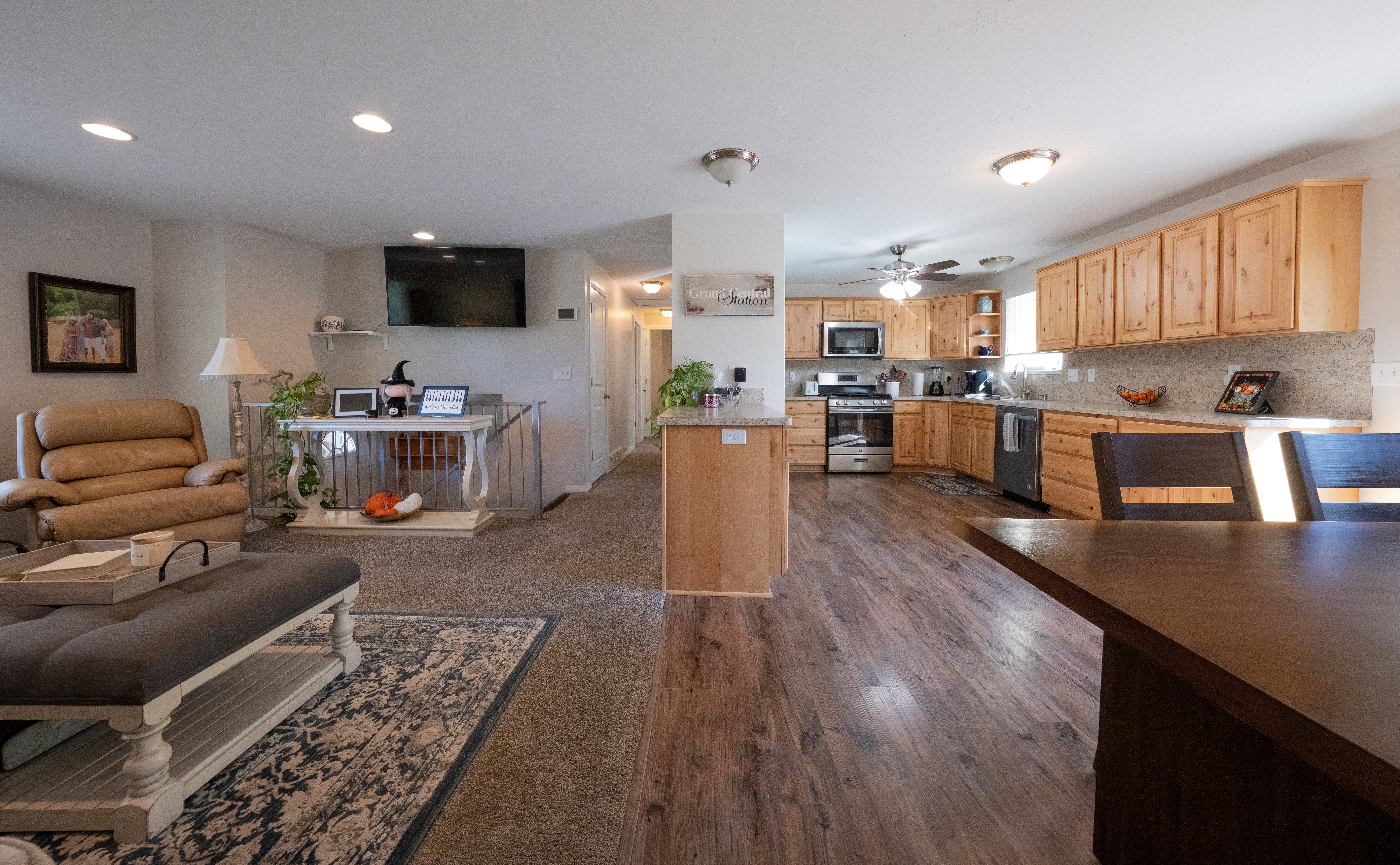 Open-concept living space featuring wood-finish flooring, recessed lighting, and a kitchen with light wood cabinetry