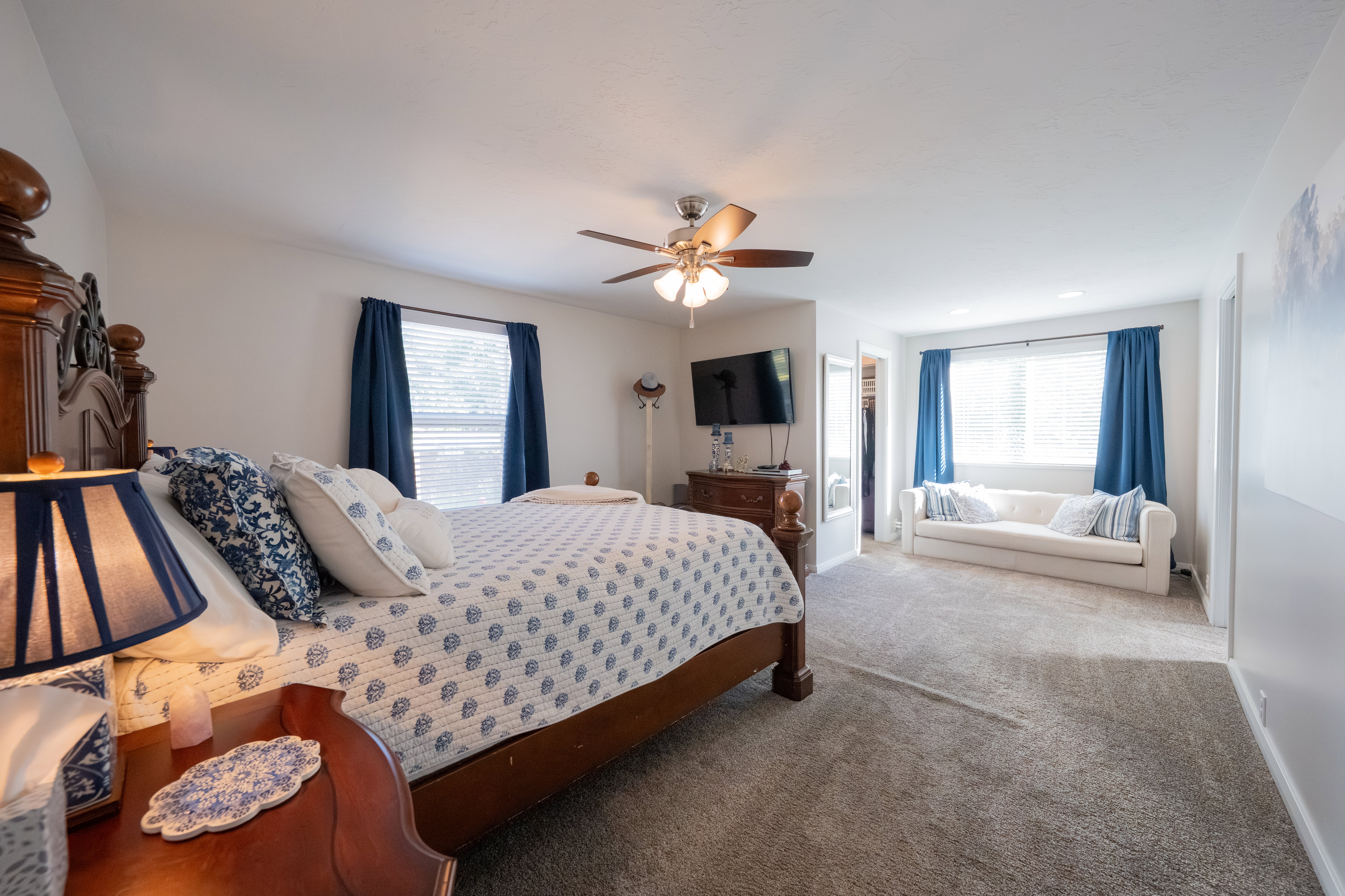 Carpeted room featuring a ceiling fan with integrated lighting, multiple windows with blinds, and white painted walls