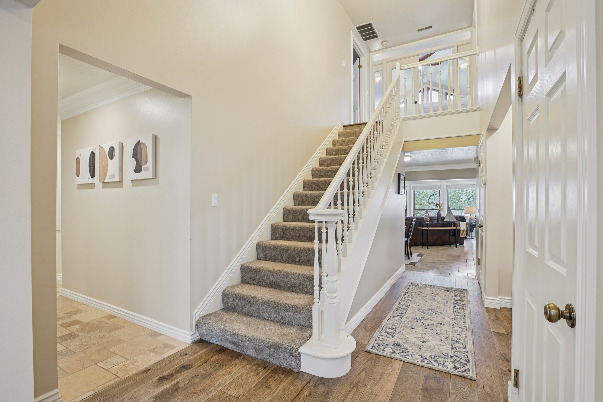Split-level entry with wood-finish flooring, a carpeted staircase with white balusters, and crown molding