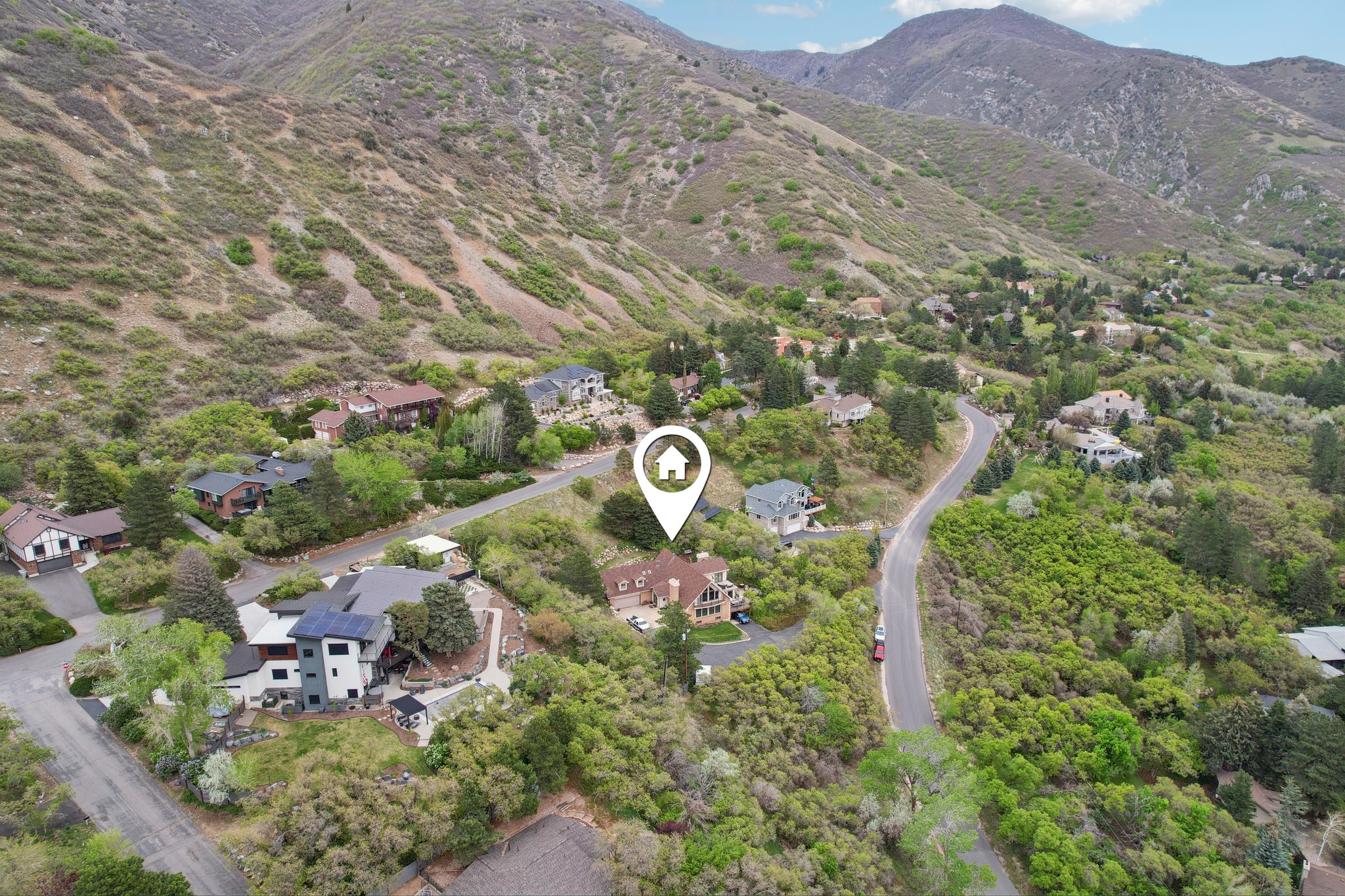 Residential property nestled into a verdant hillside with winding roads and mature trees