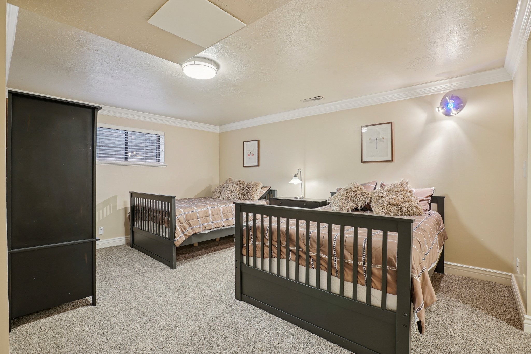Carpeted room featuring two dark-framed beds and neutral-toned walls