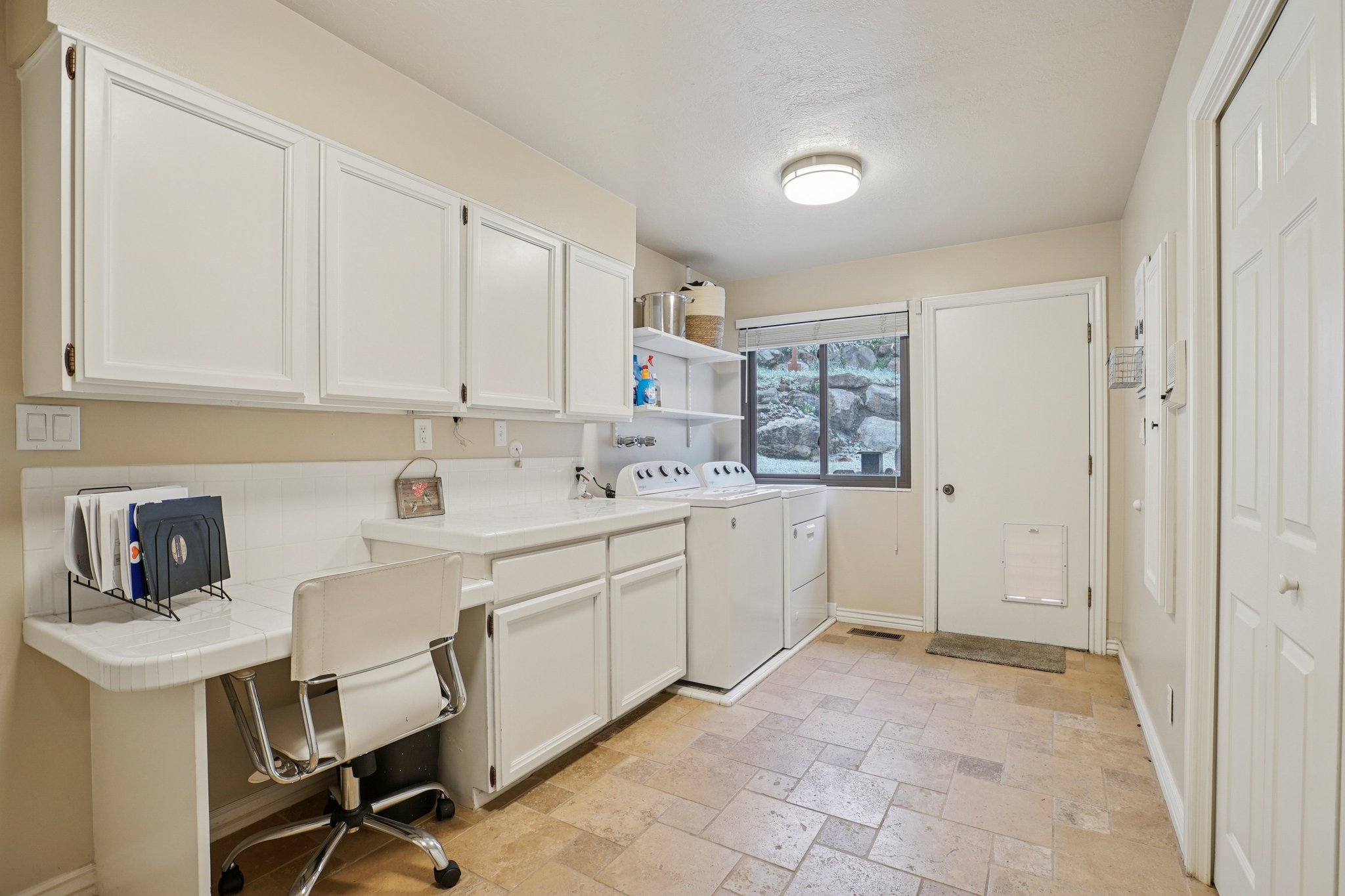 Utility room with ceramic tile flooring, white cabinetry, and a built-in desk area