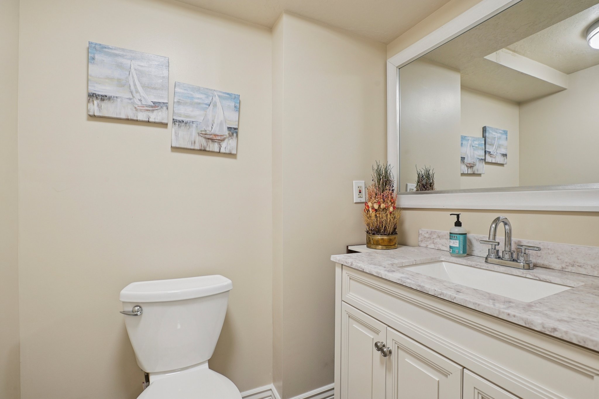 Bathroom featuring a white vanity with paneling, a rectangular undermount sink, and a speckled countertop