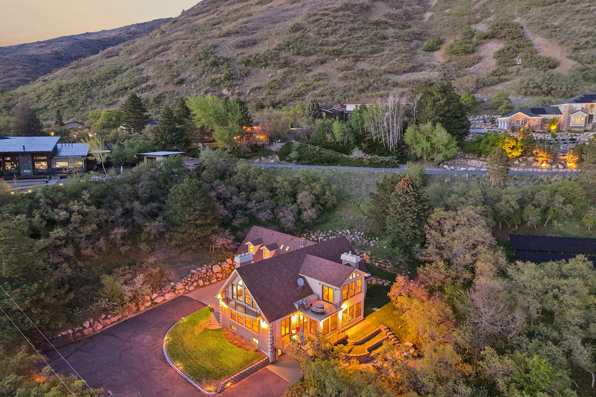 Hillside residence featuring multiple-story design, a terraced hardscaped area, and a paved driveway