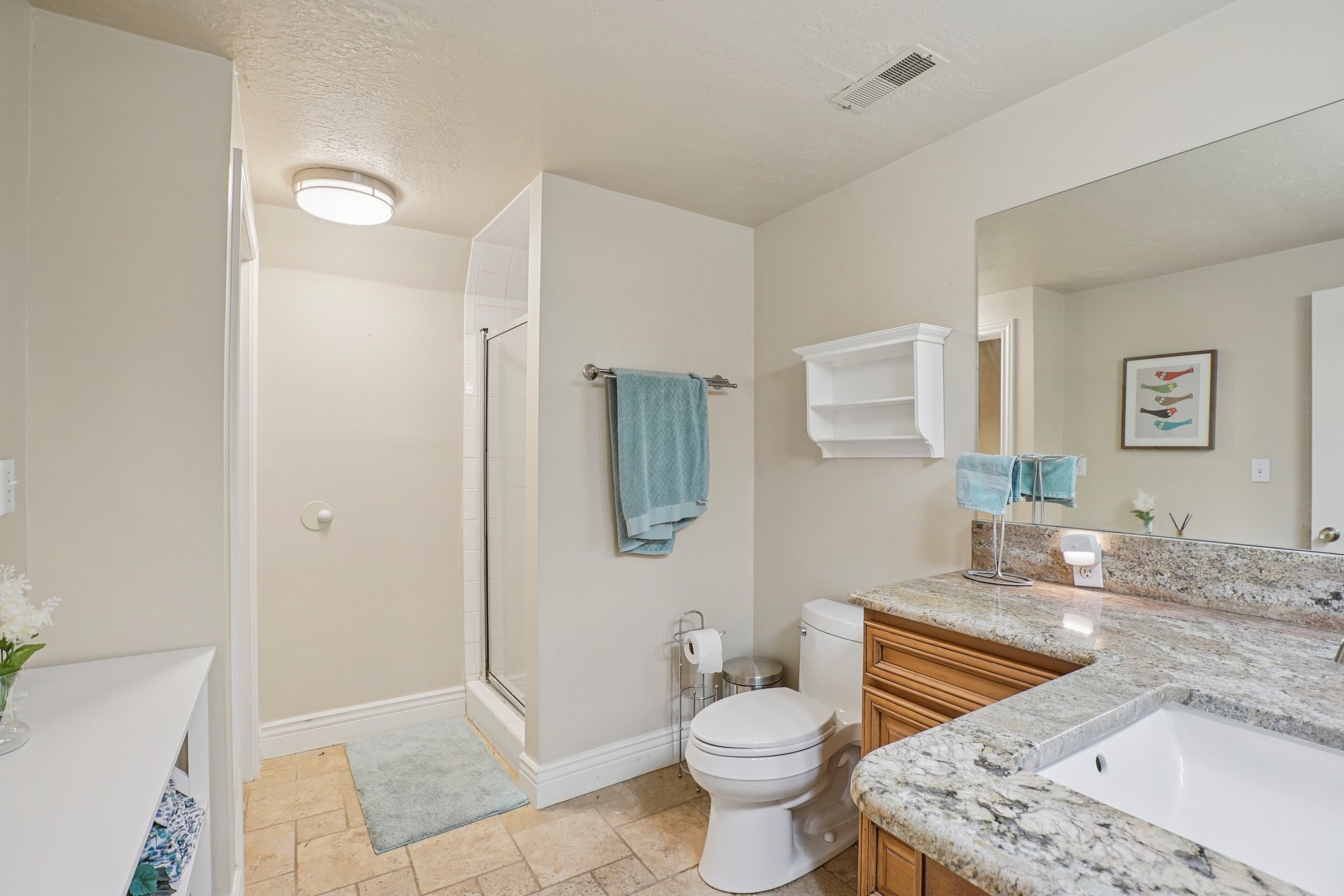 Bathroom featuring a glass-enclosed shower, a vanity with a light-toned stone countertop, an integrated sink, and wood-finish cabinetry