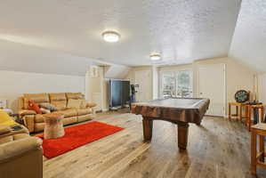 Spacious room featuring wood-finish flooring, light-toned walls, and recessed lighting