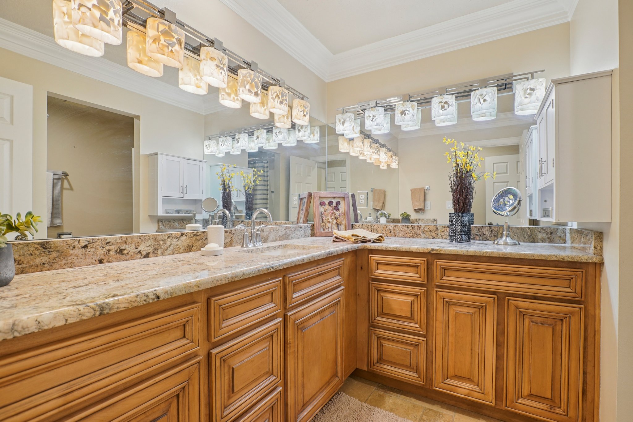 Expansive vanity featuring twin undermount sinks, stone countertops, and extensive wood cabinetry