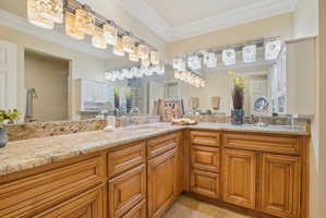 Expansive vanity featuring twin undermount sinks, stone countertops, and extensive wood cabinetry