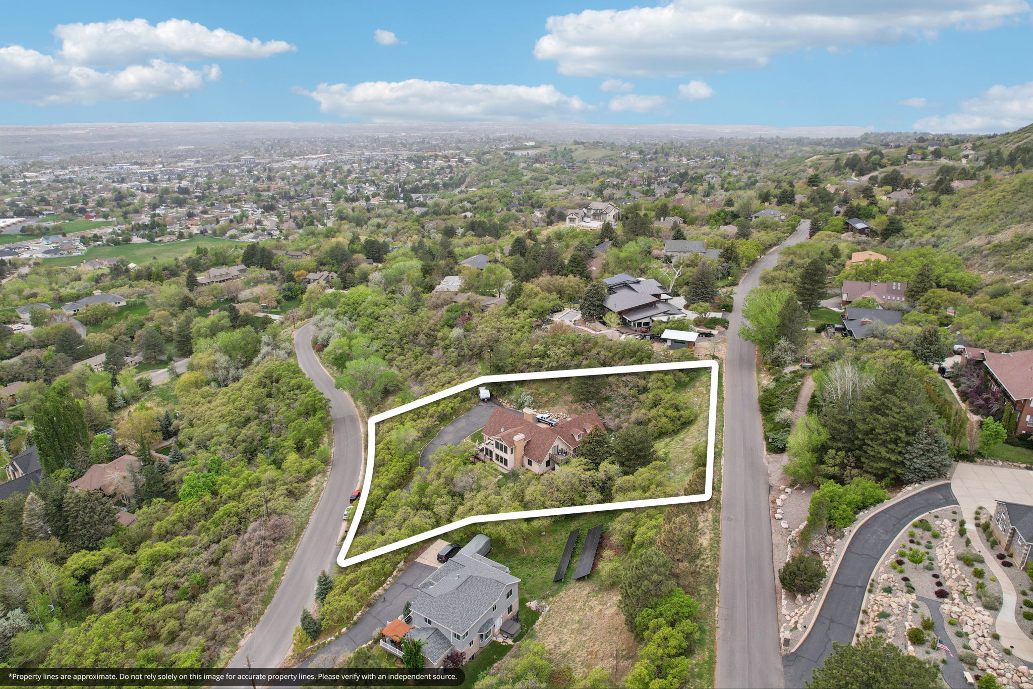 Hillside property featuring a multi-level residence with a red tile roof and multiple gables